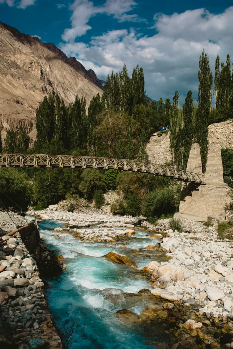 Wooden bridge over a river gorge between bare mountains