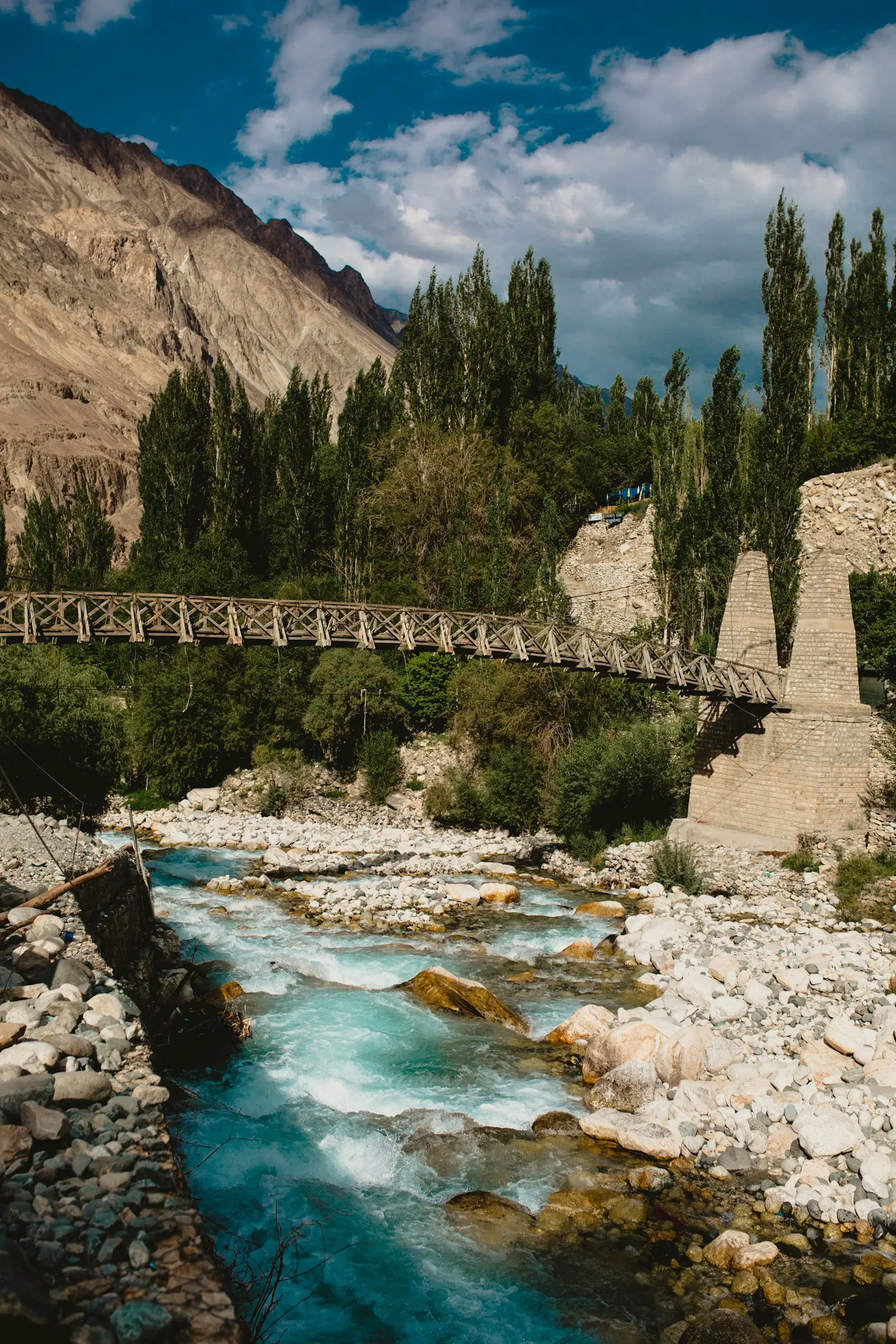 Wooden bridge over a river gorge between bare mountains