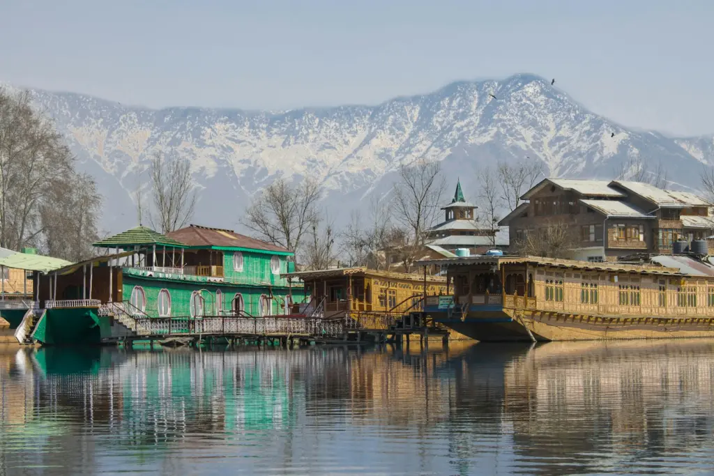 Wooden houseboats on the lake below snow-covered mountains, Srinagar