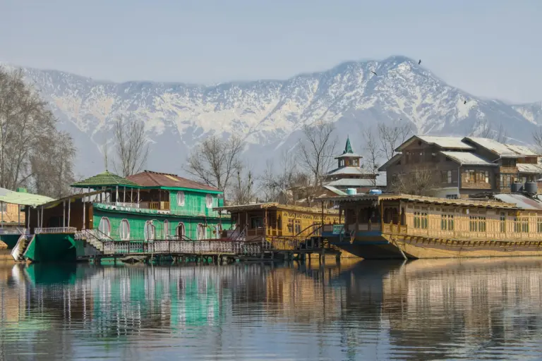 Wooden houseboats on the lake below snow-covered mountains, Srinagar
