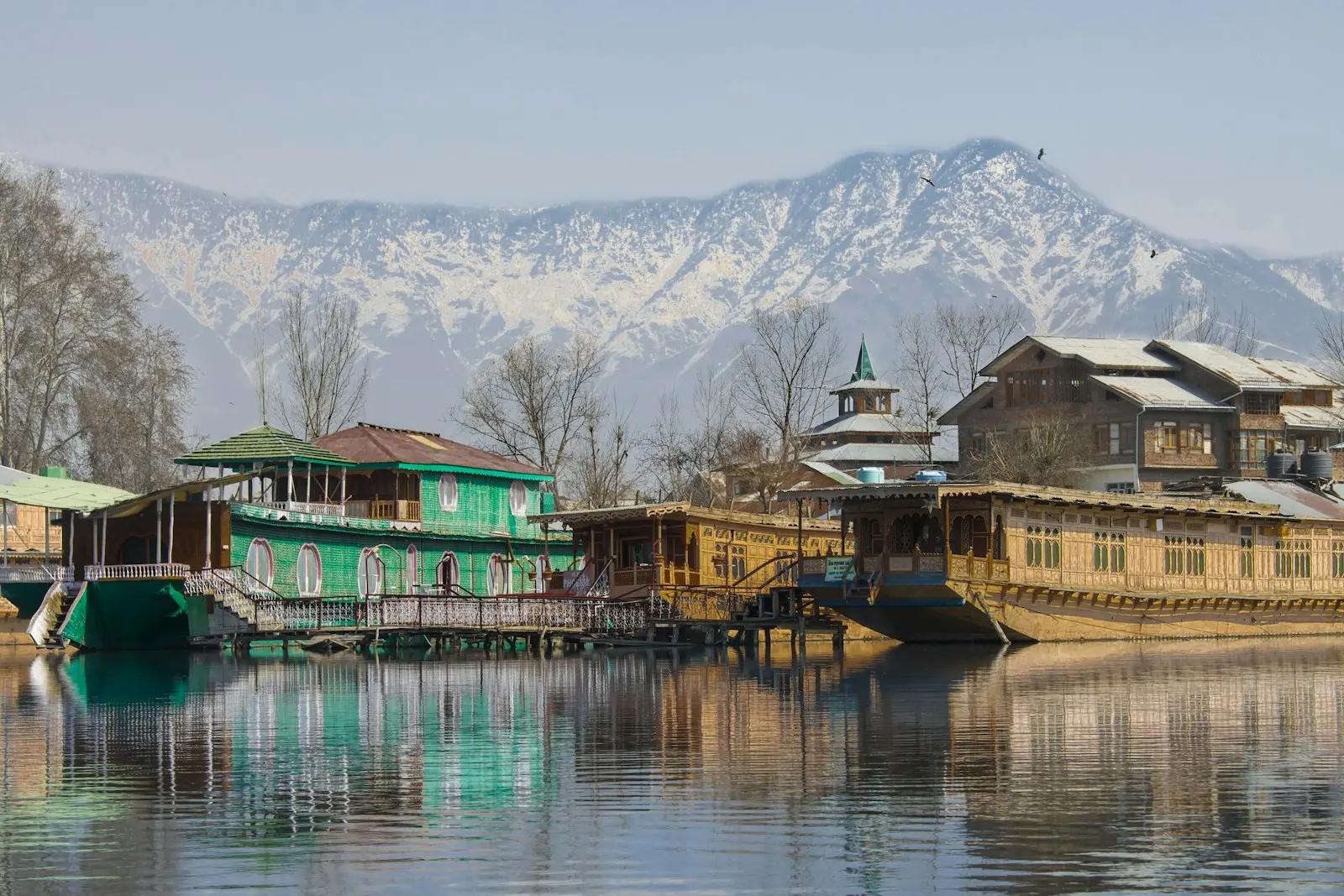 Wooden houseboats on the lake below snow-covered mountains, Srinagar