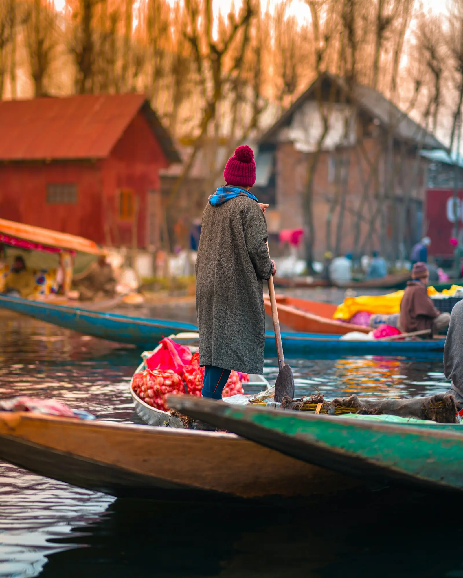 Boatman in a red cap paddling a wooden boat loaded with fresh produce