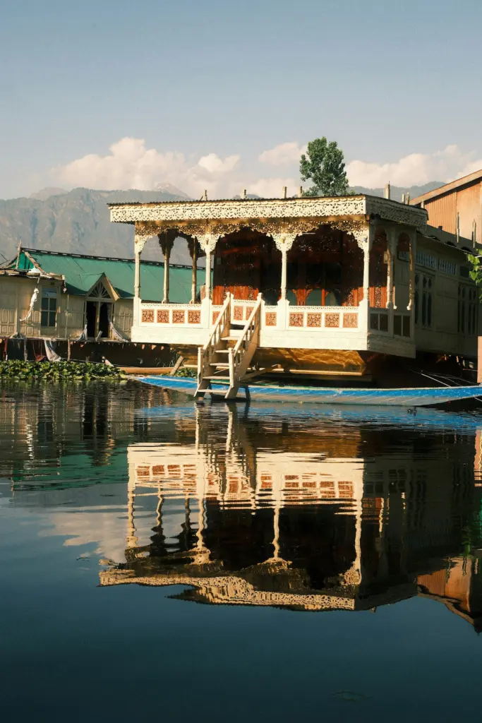 Carved wooden houseboat reflected in calm water on Dal Lake
